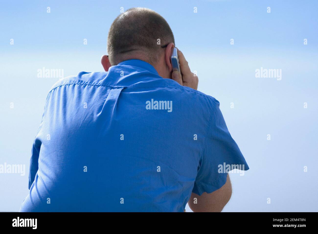 Rear view of a man using a mobile phone Stock Photo