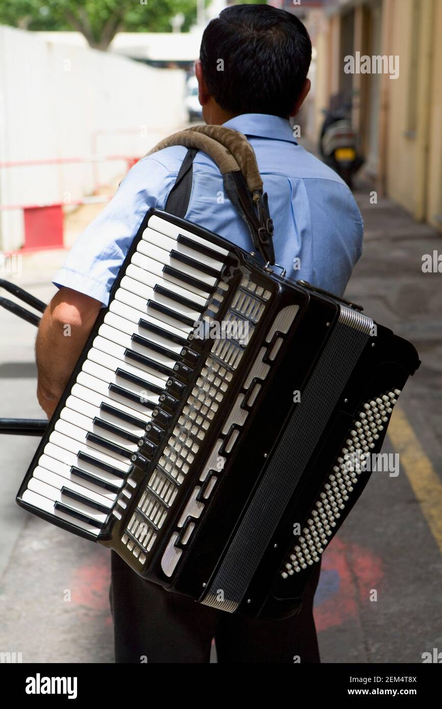 Rear view of a musician carrying an accordion Stock Photo