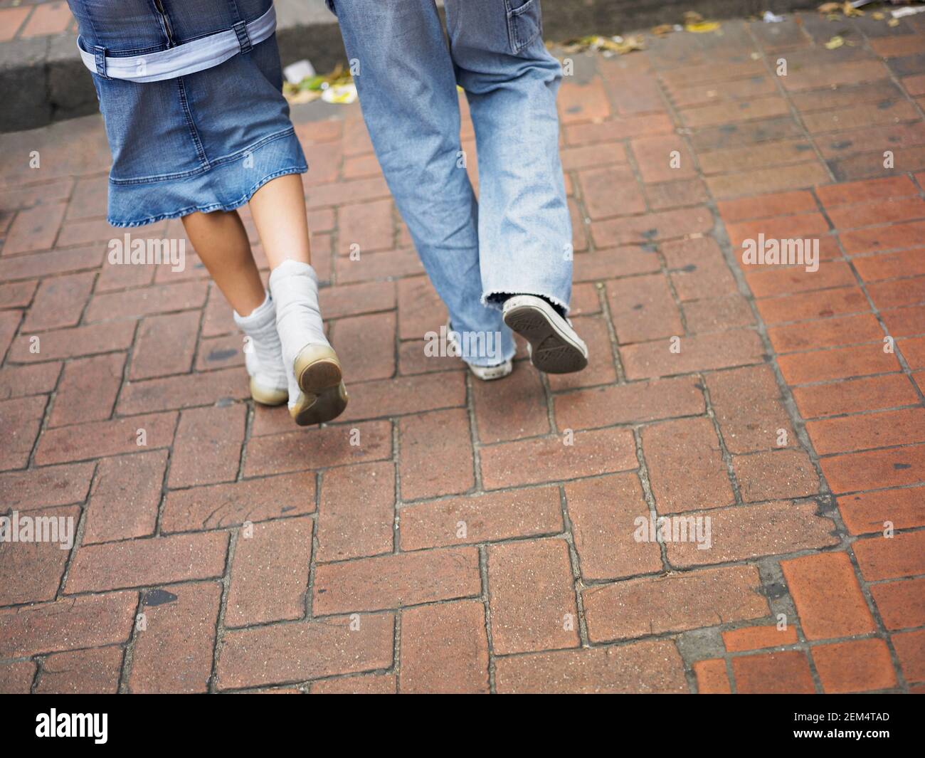 Low section view of a man and a woman walking on the sidewalk Stock Photo