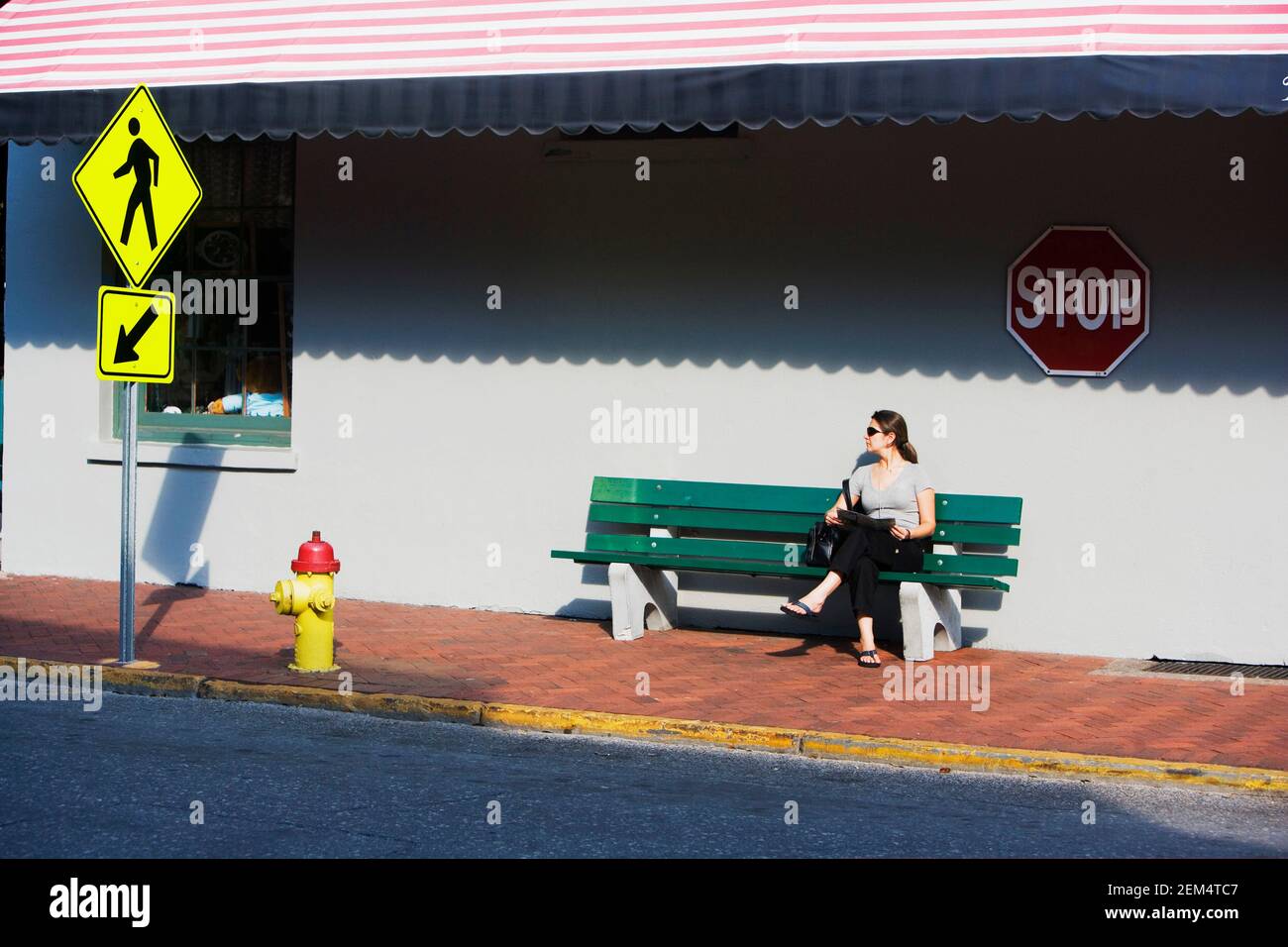 Mid adult woman sitting on a bench near the road Stock Photo