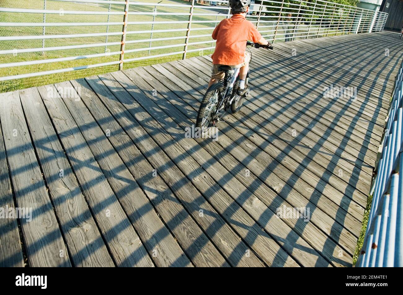 Rear view of a boy riding a bicycle over a bridge Stock Photo