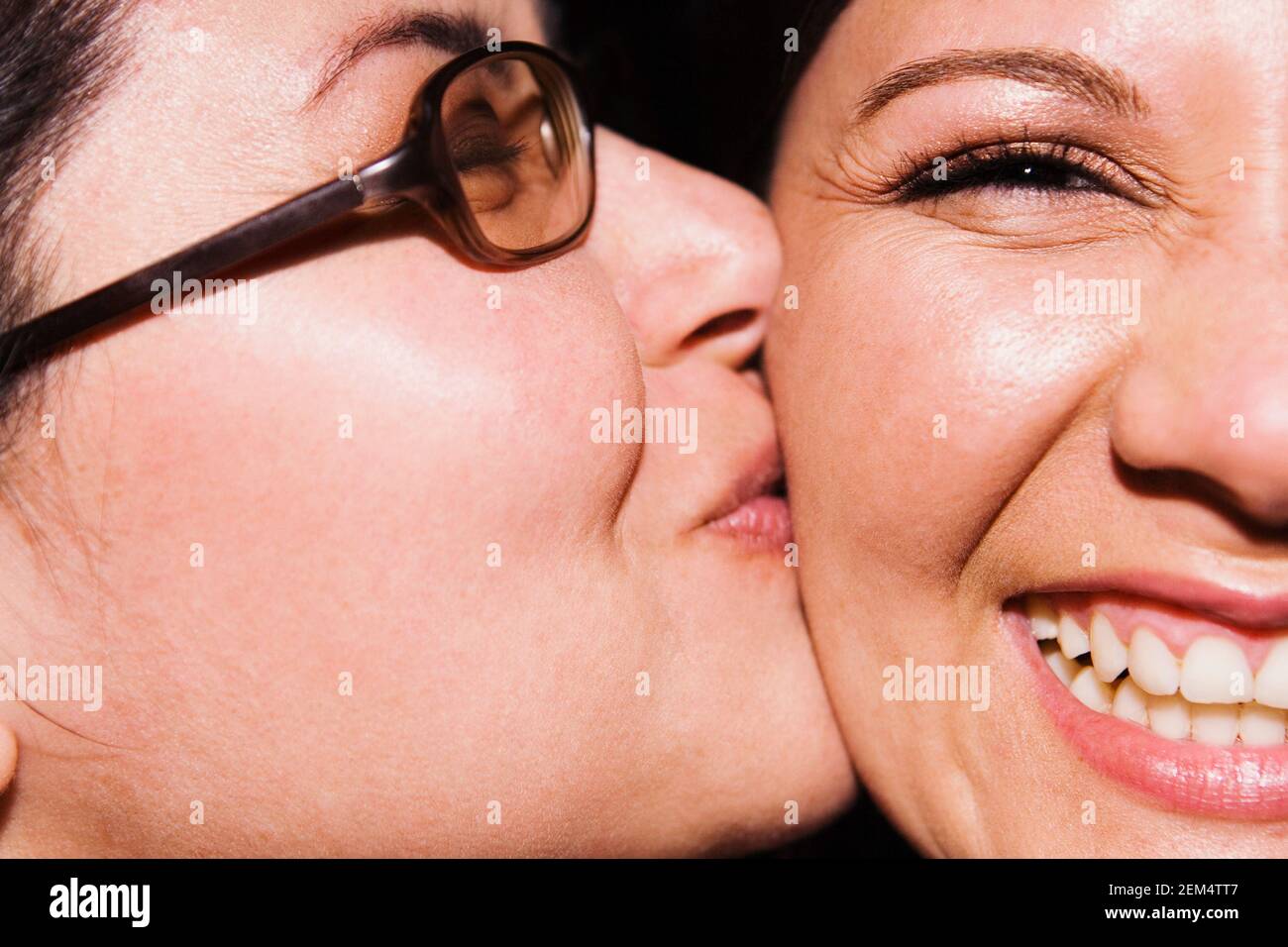 Portrait of a young woman kissed by her friend on her cheek Stock Photo