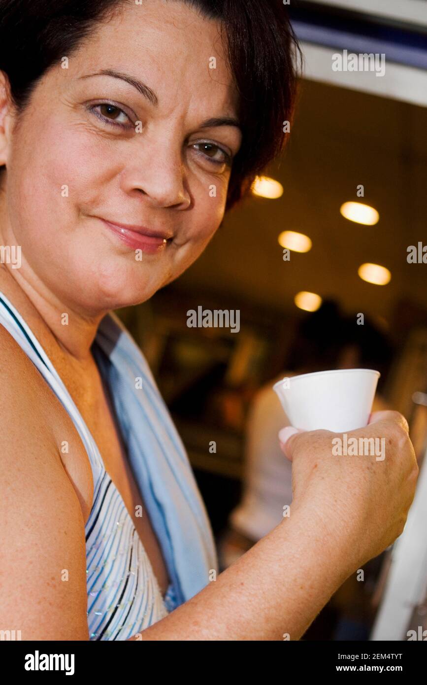 Portrait of a mature woman smiling and holding a disposable cup Stock Photo