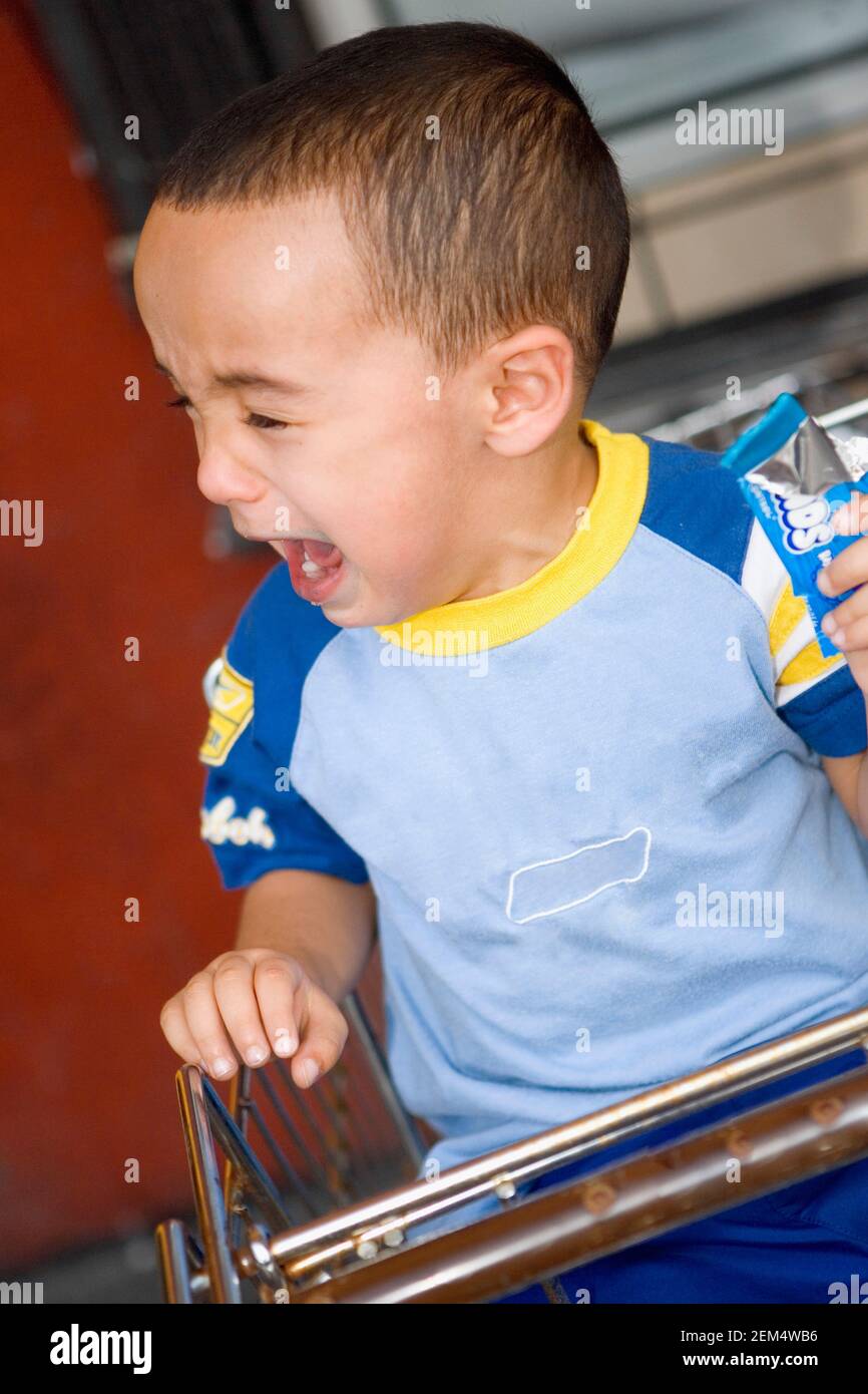 Close-up of a boy sitting in a shopping cart and crying Stock Photo