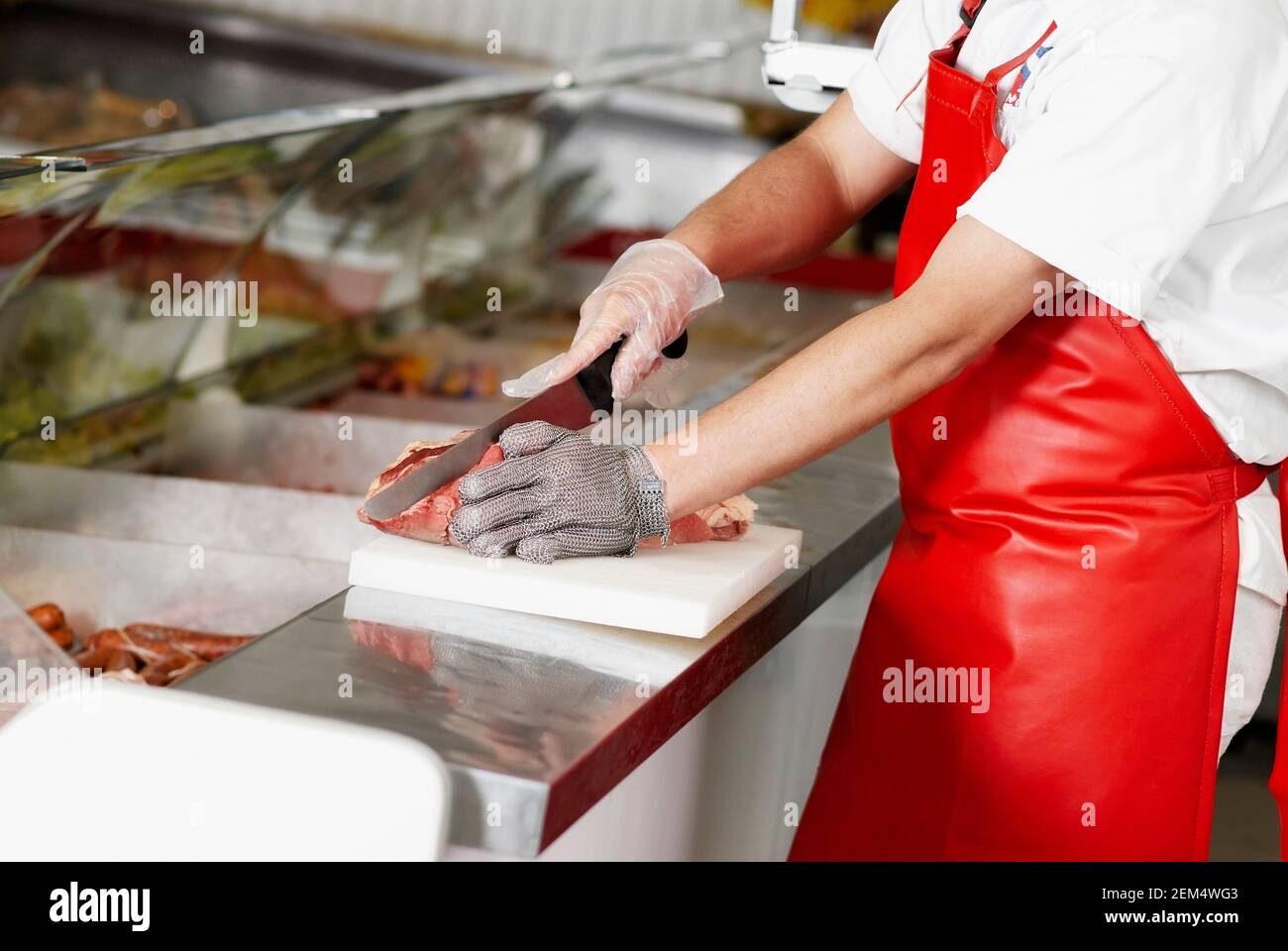 Close-up of a butcher cutting meat in a butcher shop Stock Photo