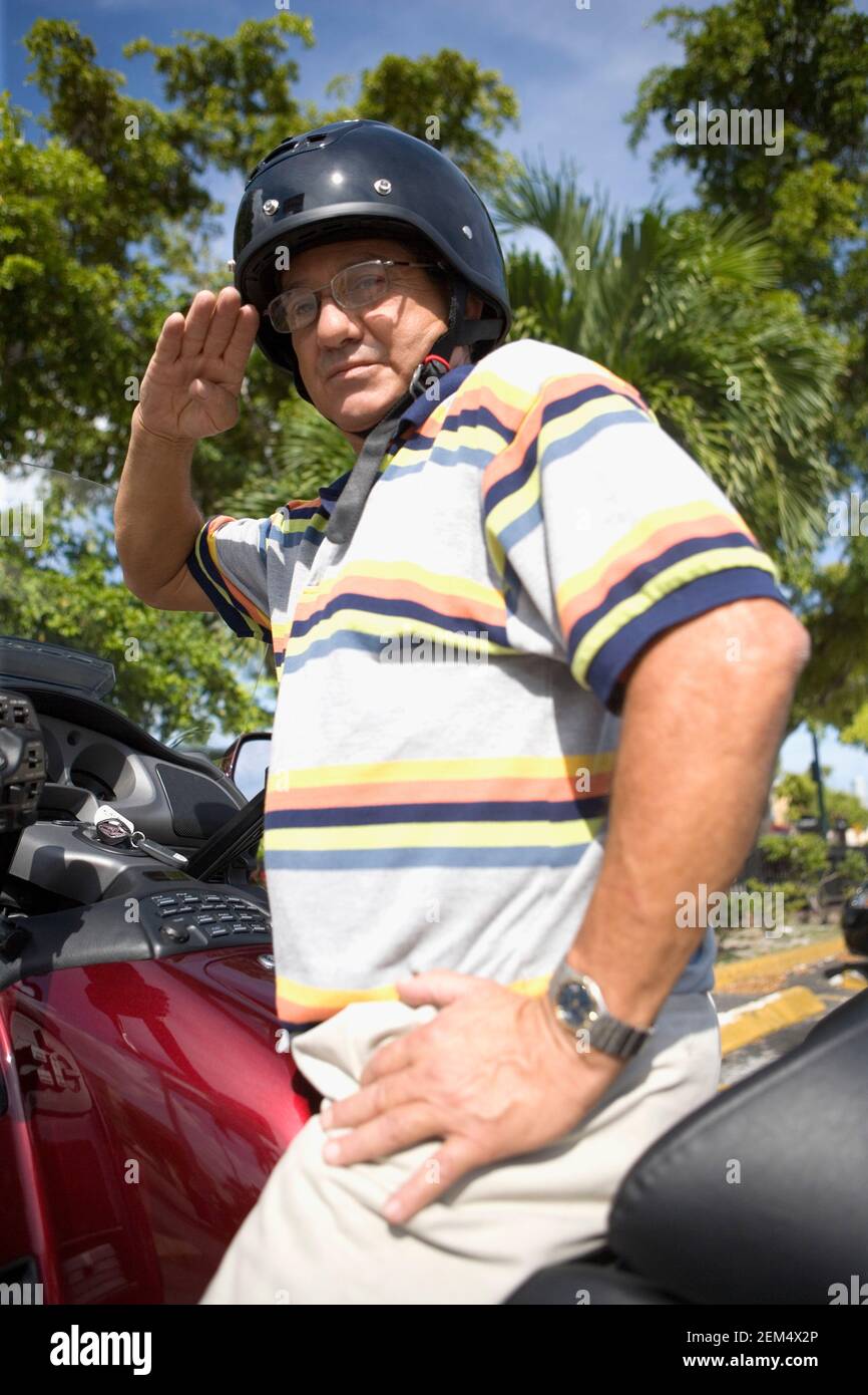 Portrait of a mature man saluting on a motorbike Stock Photo