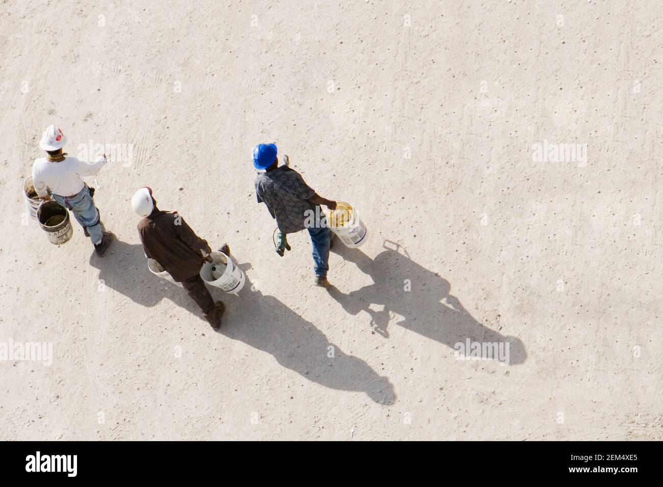 High angle view of three construction workers carrying buckets Stock Photo