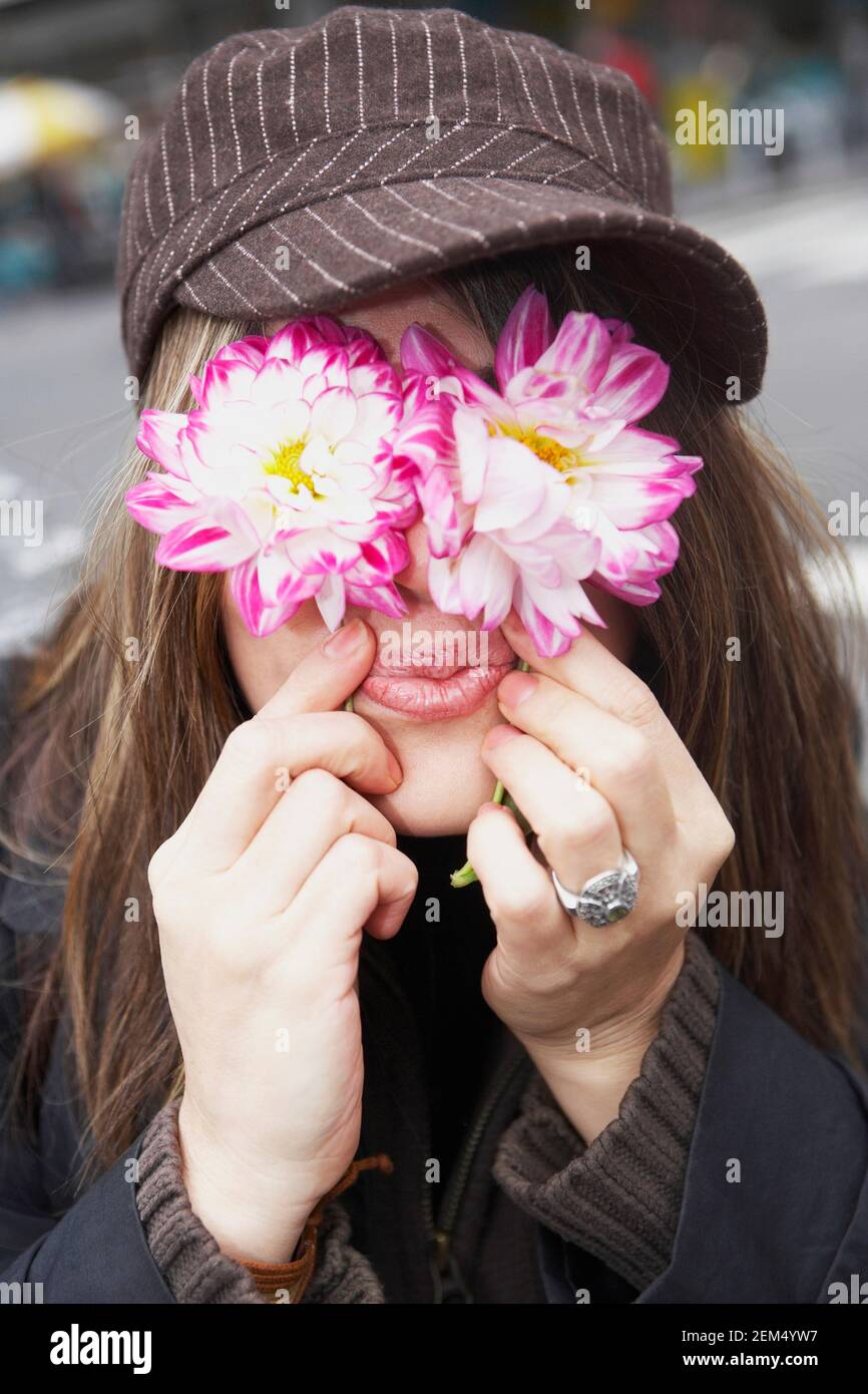 Close-up of a young woman covering her eyes with flowers Stock Photo