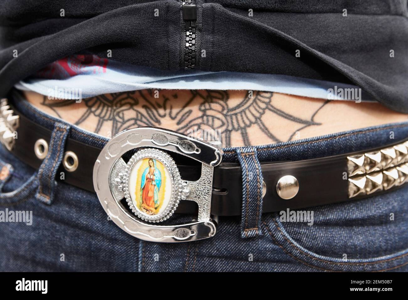 Mid section view of a woman with a belt and a tattoo on her stomach Stock Photo