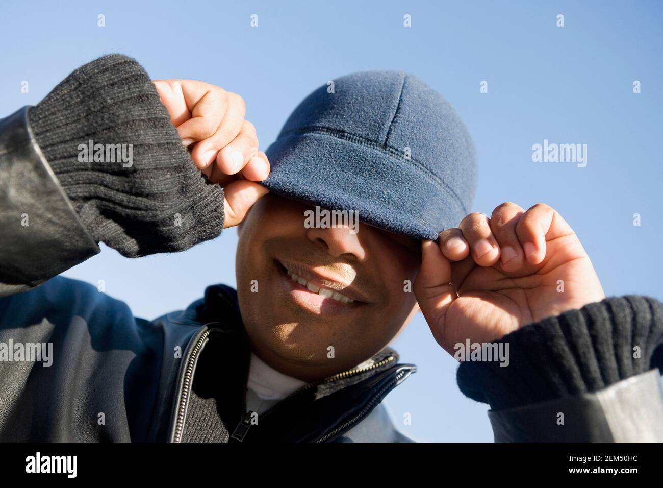 Low angle view of a man adjusting his hat and smiling Stock Photo