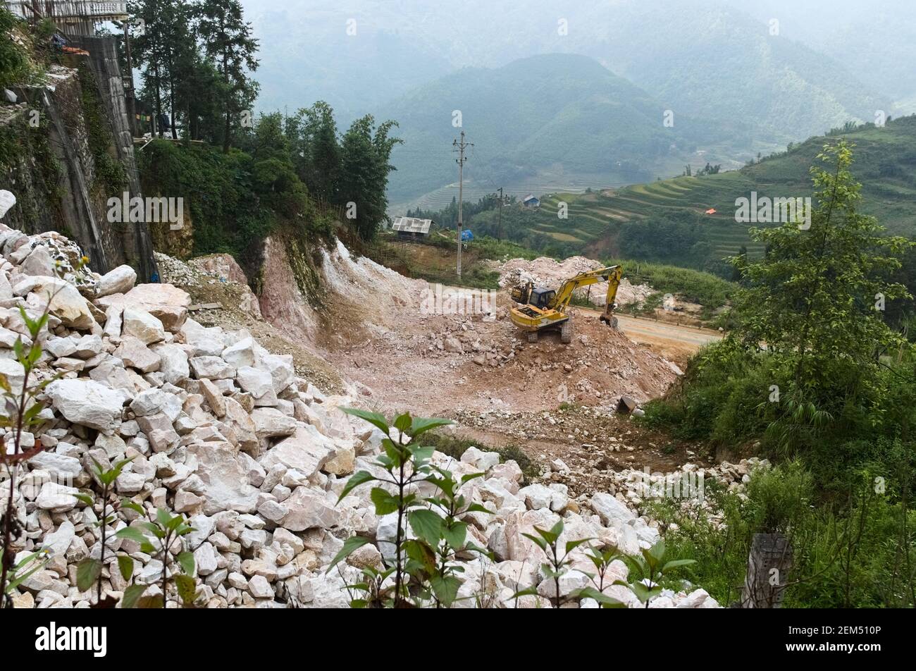 Excavator digging ground. Construction site with heavy machinery equipment. Large pile of stones and gravel. Stunning view to the valley and mountains Stock Photo
