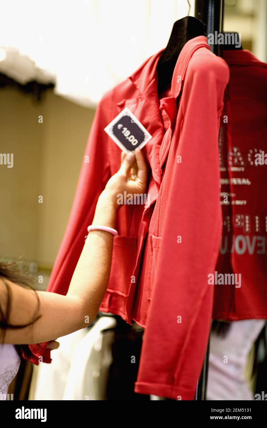 Close-up of woman's hand checking the price tag of a coat in a clothing store Stock Photo