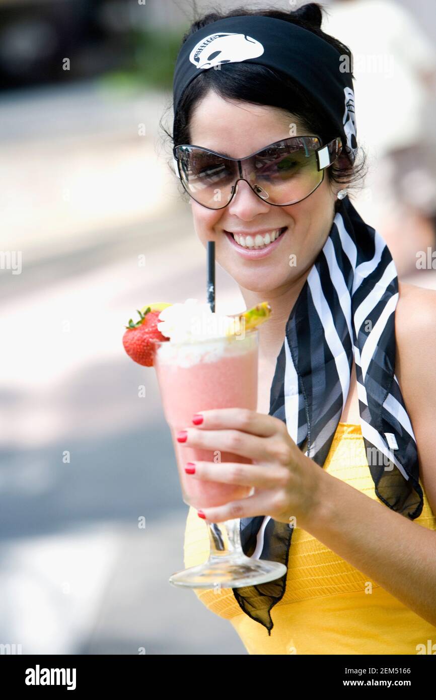 Close-up of a mid adult woman holding a glass of juice and smiling Stock Photo