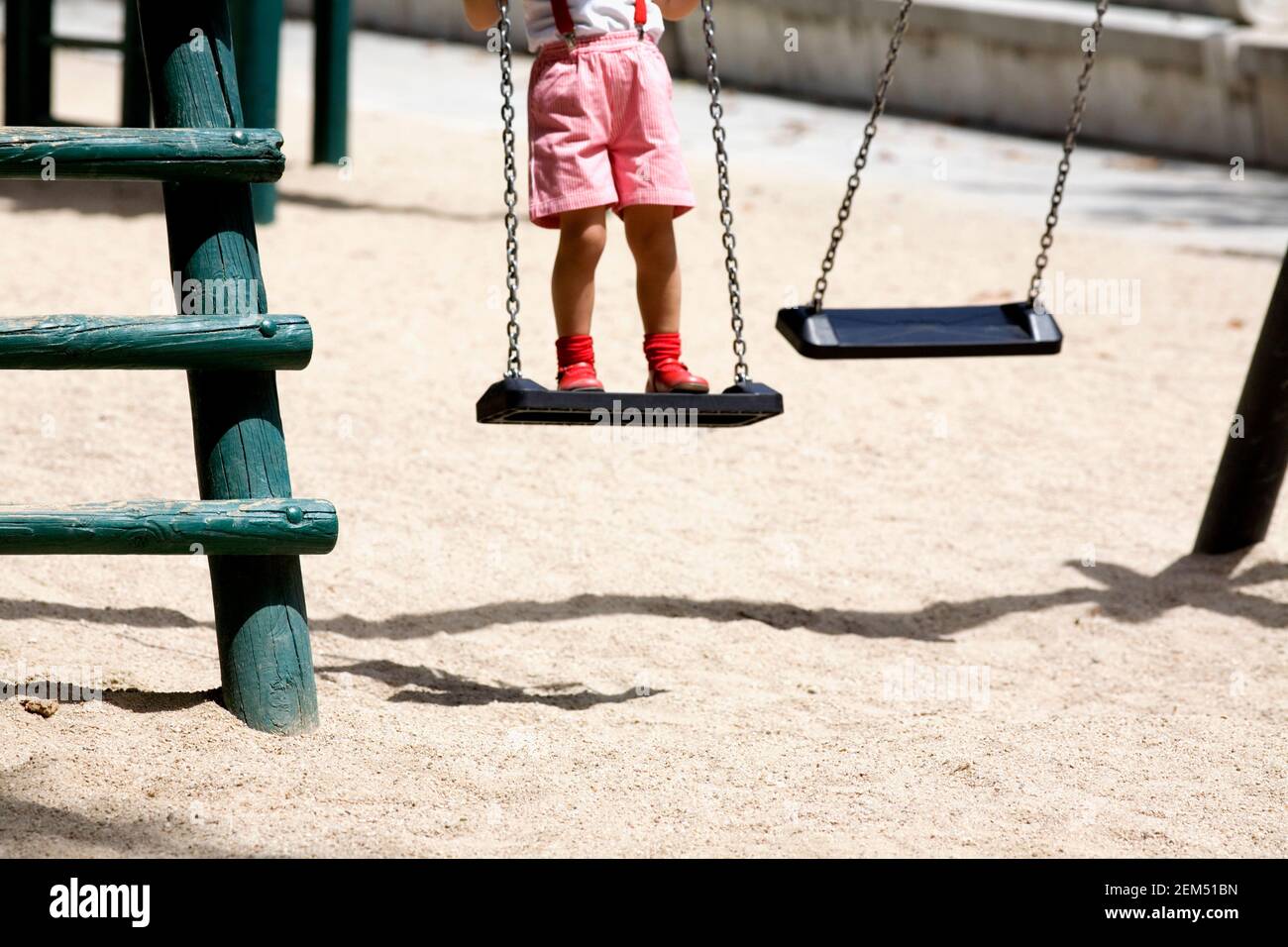 Low section view of a girl standing on a swing Stock Photo - Alamy