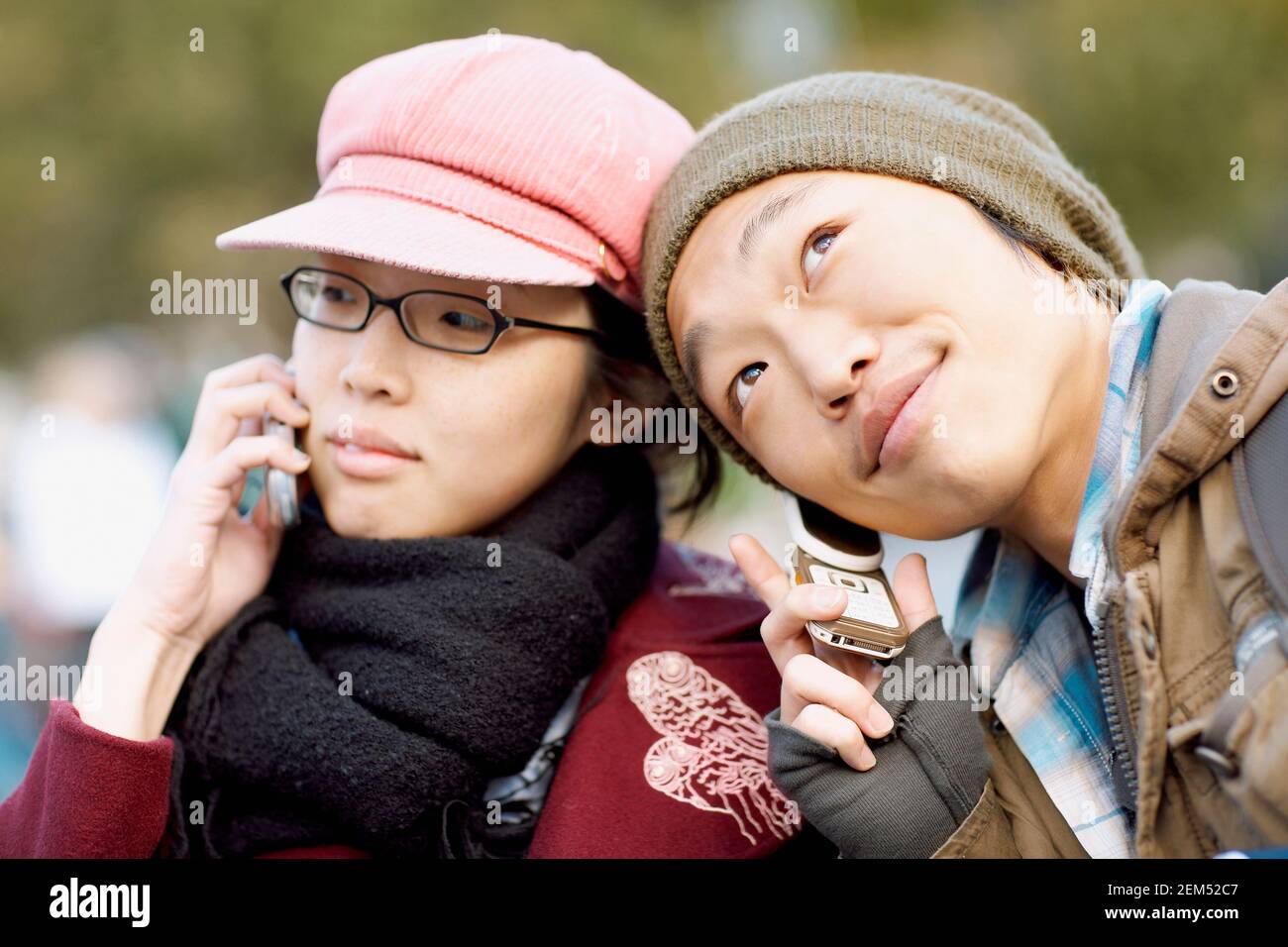 Close-up of two young women listening to mobile phones Stock Photo