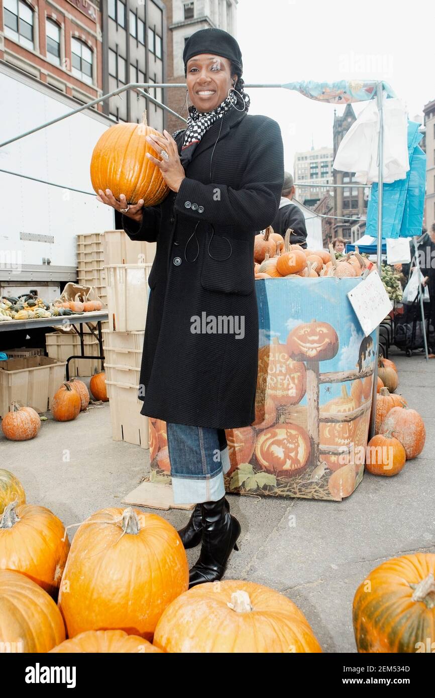 Portrait of a mid adult woman holding a pumpkin in a vegetable market Stock Photo