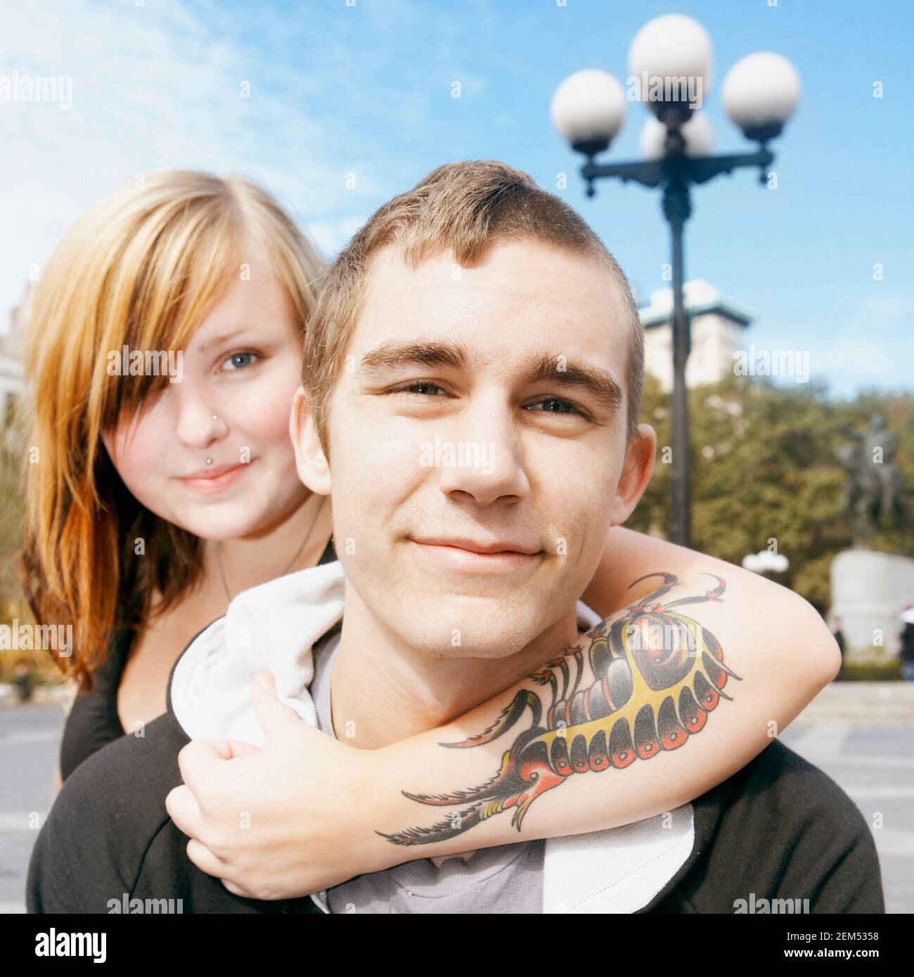 Portrait of a young woman embracing a young man from behind Stock Photo