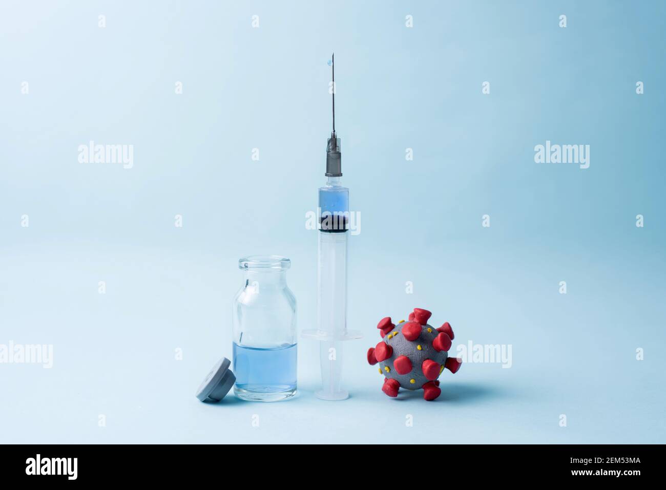Coronavirus model, a syringe with vaccine and vaccine bottle on blue ...