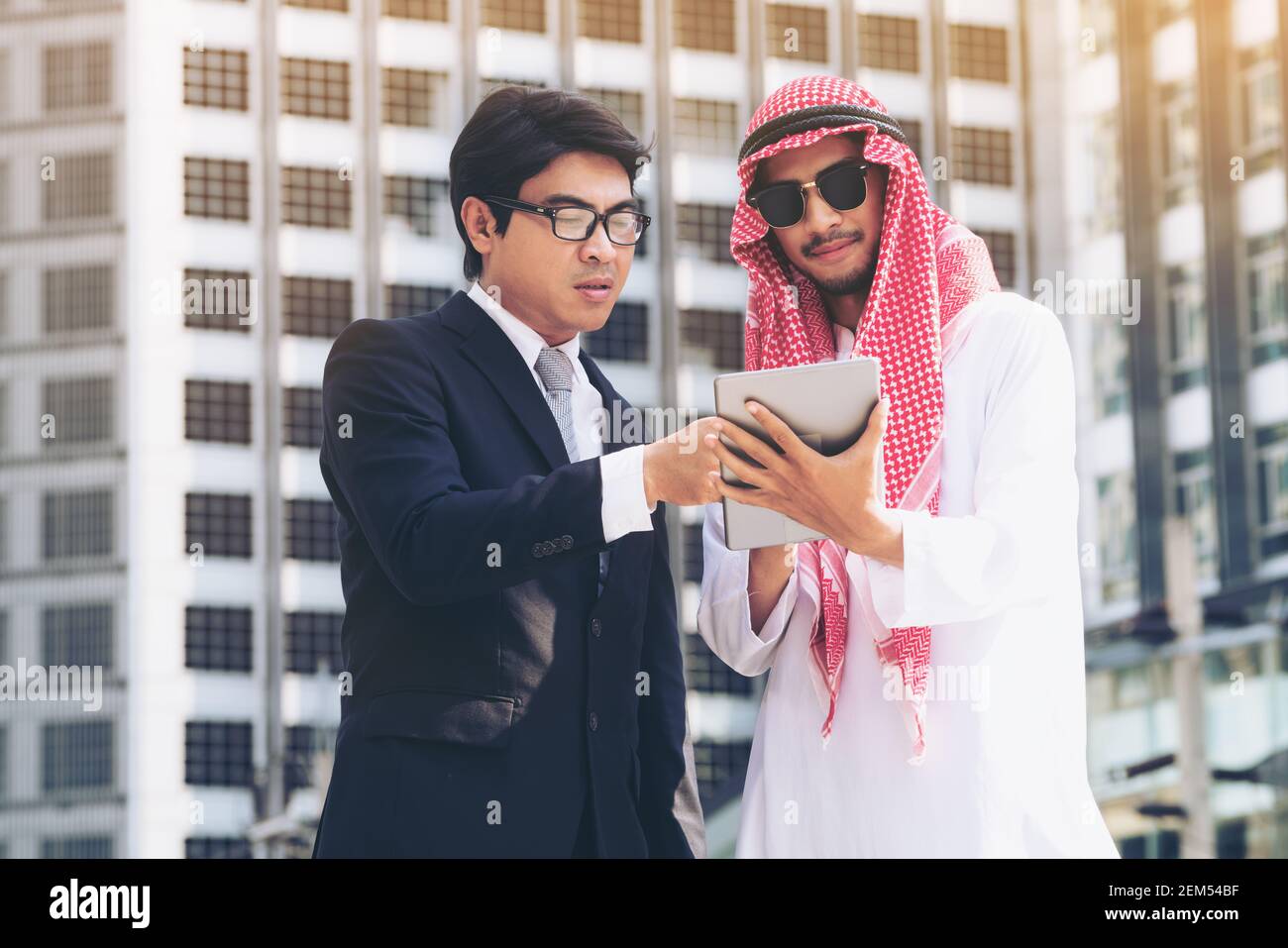 Arab man and businessman discuss content in tablet computer. Multicultural international oversea business meeting. Stock Photo