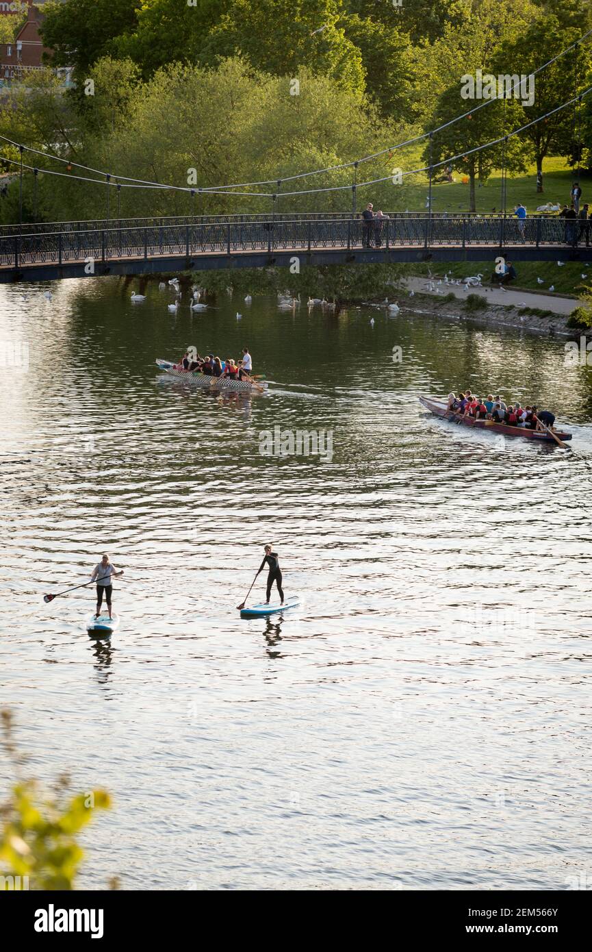 Stand-Up Paddleboarders and Dragonboat Racers on the River Exe at Exeter Quay, Exeter, Devon, UK. Stock Photo
