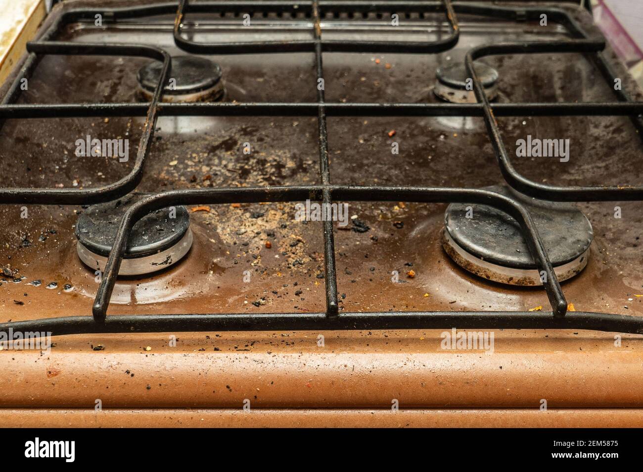 The gas stove is covered in grease and stains of dirt.Unsanitary