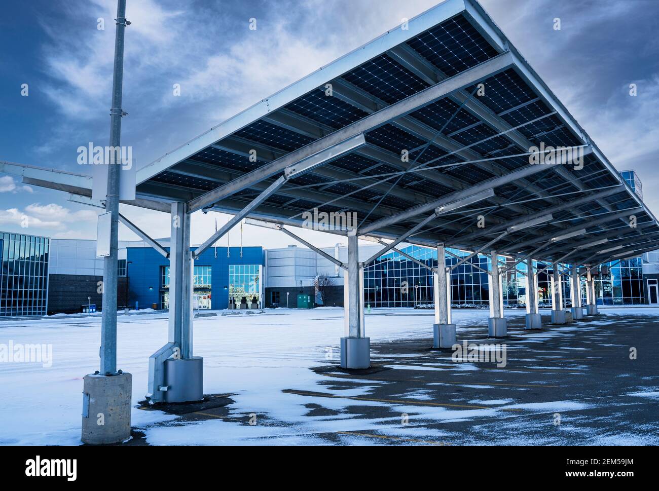 A modern solar carport for public vehicle parking is outfitted with solar panels producing renewable energy. Stock Photo