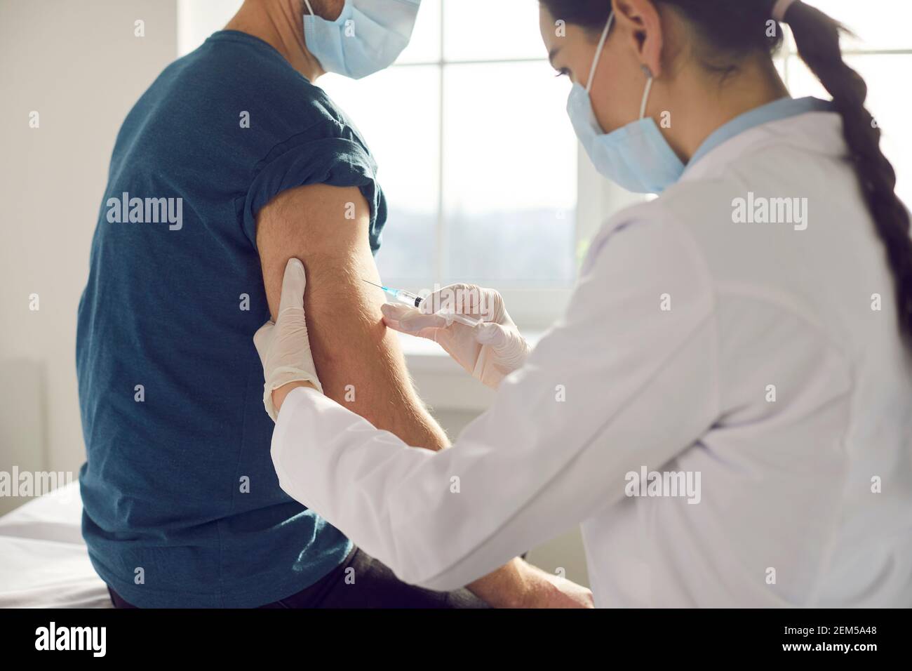 Female medical worker injecting vaccine and making vaccination for man Stock Photo