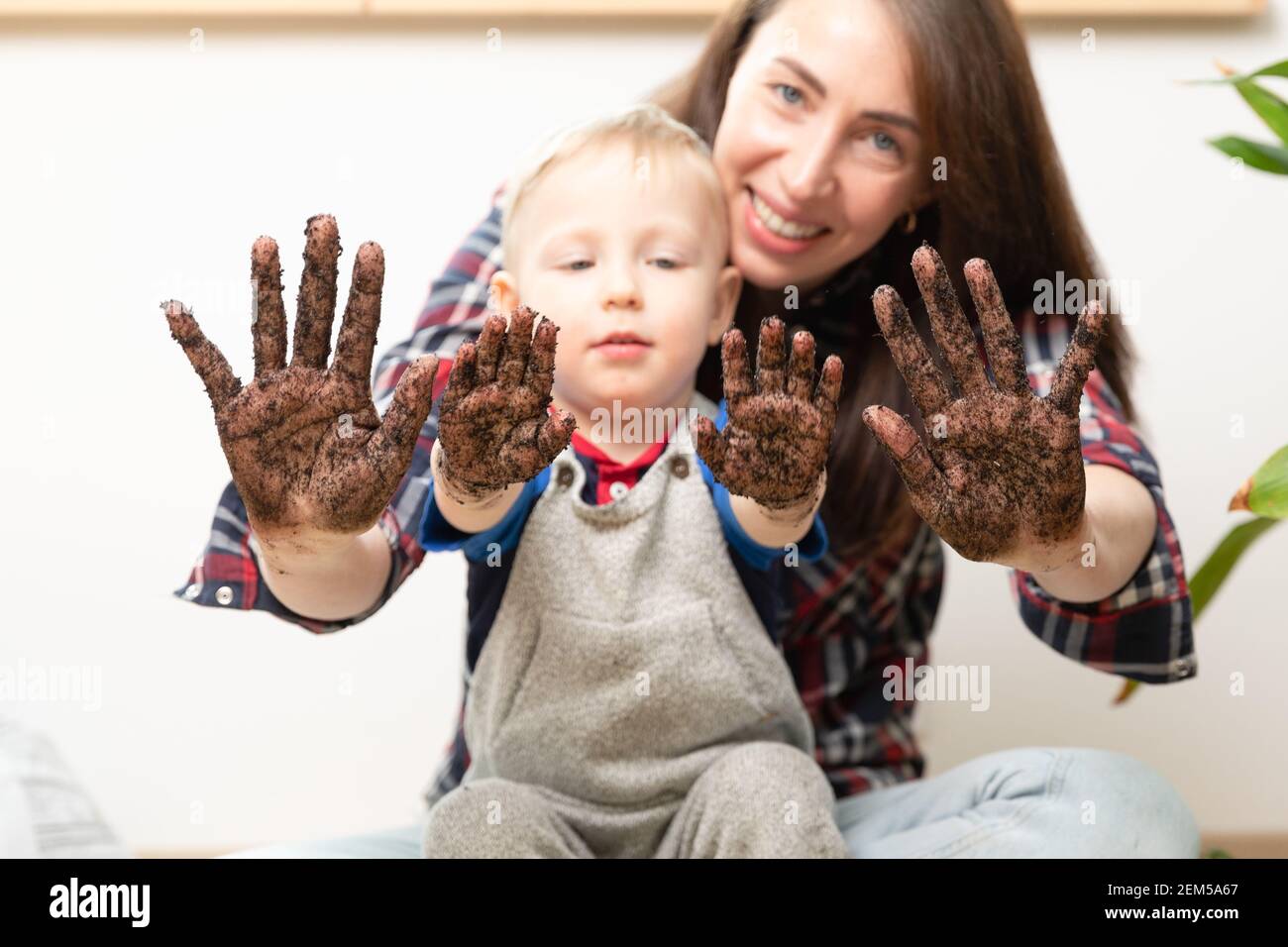 Hobbies at home gardening learning botany - young mother and child showing hands covered in dirt. Stock Photo