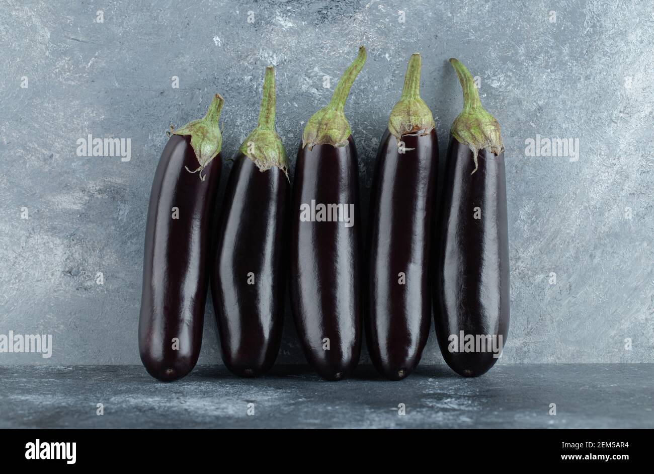 organic ripe aubergine row on grey background Stock Photo