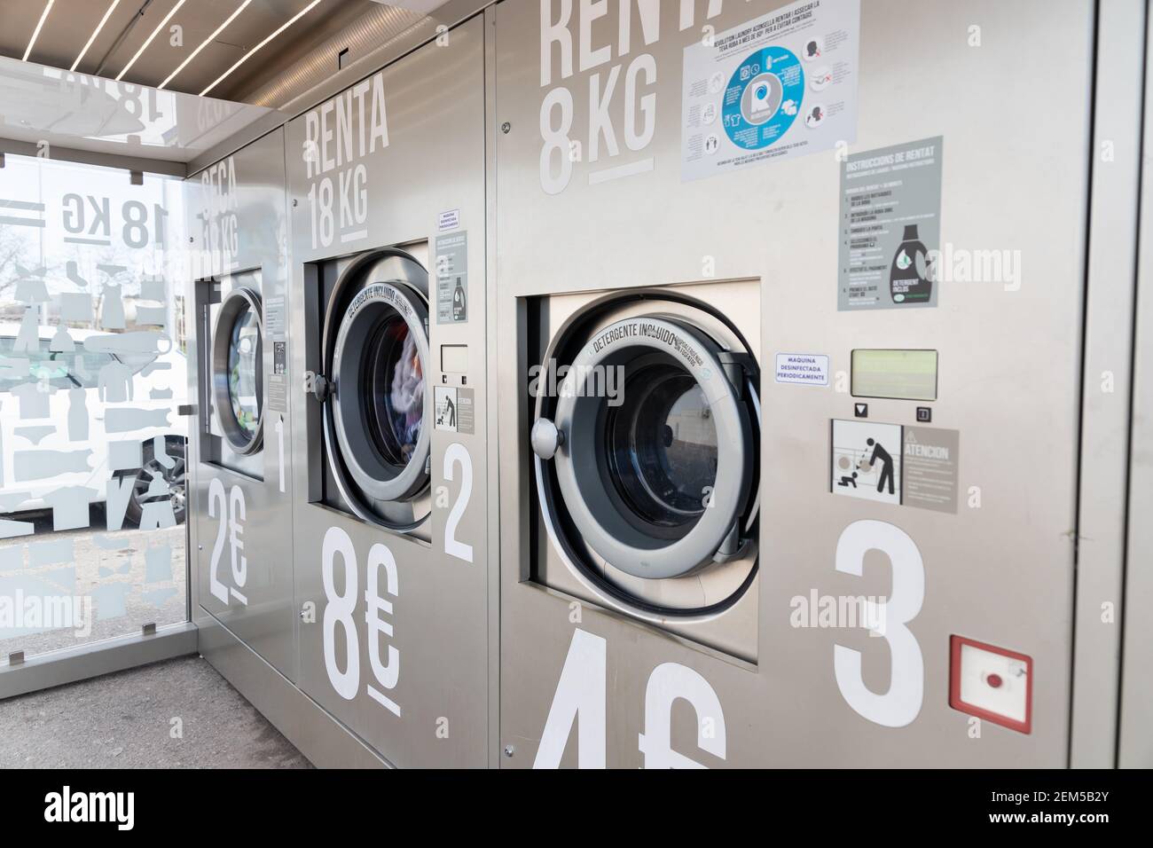 CALDES DE MONTBUI, SPAIN - 31 JANUARY 2021:Washing machines in a self service laundry place in Spain outdoors. Written in spanish ¨ Detergent included Stock Photo