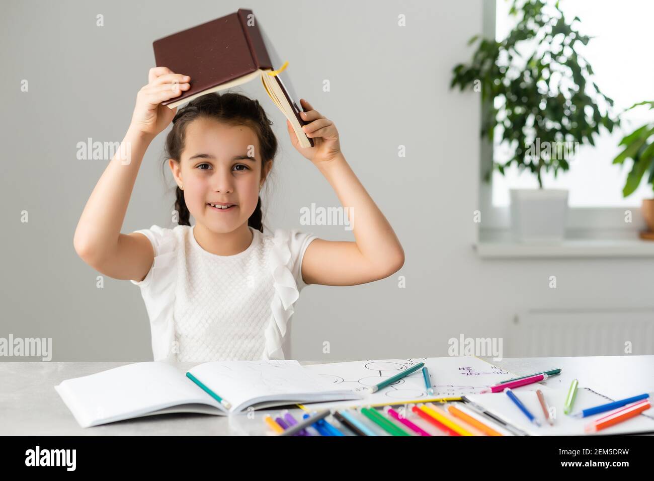 Cute little girl studying at home and smiling Stock Photo - Alamy