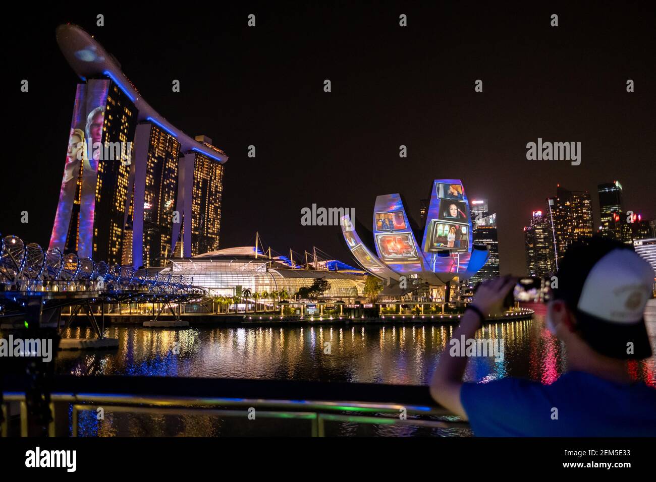 A man takes photos of the Disney+ showcase that was projected at the Singapore ArtScience Museum and the Marina Bay Sands Singapore.Disney+ was launched in Singapore on the 24th February 2021, making the country the first in the world to receive Disney+ which consists of Disney, Marvel, Star Wars, Pixar, National Geographic, and Star War, giving access to Singapore consumers to over 650 films and 15,000 episodes from the mentioned brands. Stock Photo