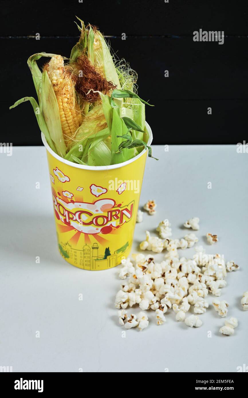 Corns in paper cup and popcorn on white table Stock Photo - Alamy