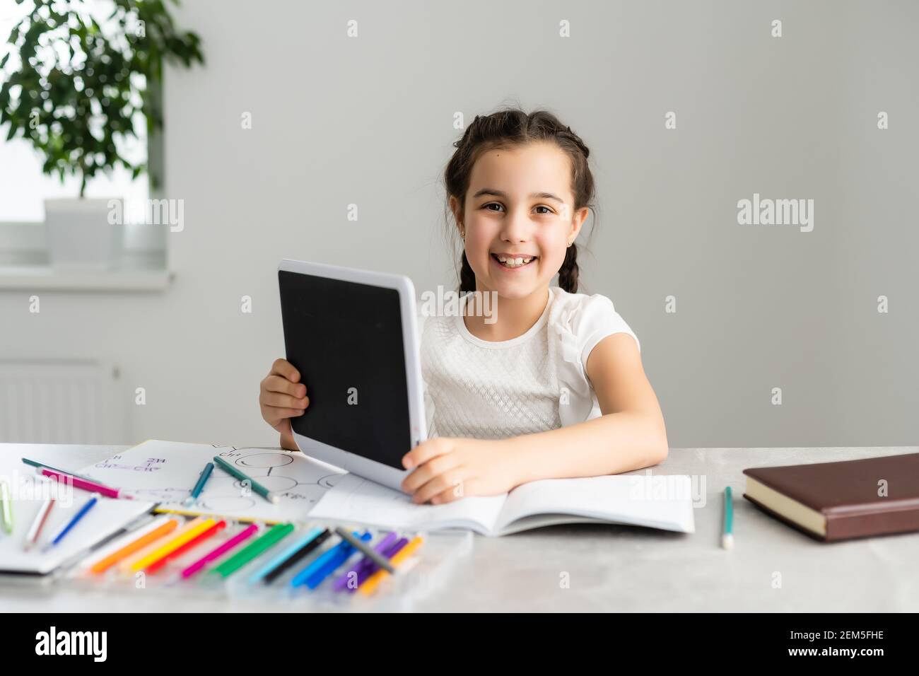 Cute little girl studying at home and smiling Stock Photo - Alamy