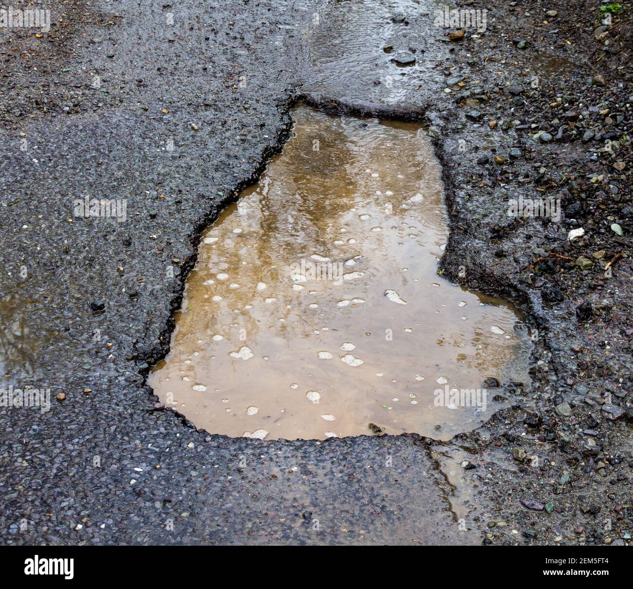 Pothole or pot hole damage in road surface Stock Photo