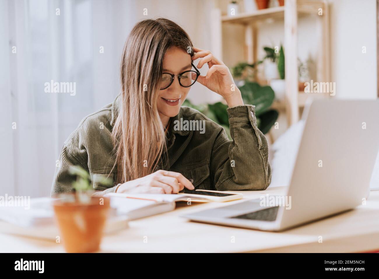 Woman writes in notebook with laptop Stock Photo