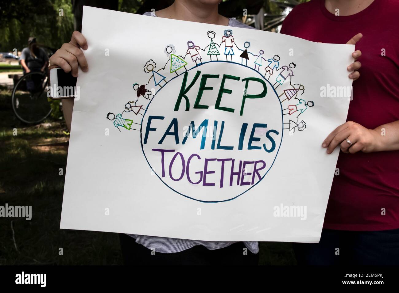 Two women at protest holding homemade sign together that says keep families together with world and families holding hands on it - cropped and selecti Stock Photo