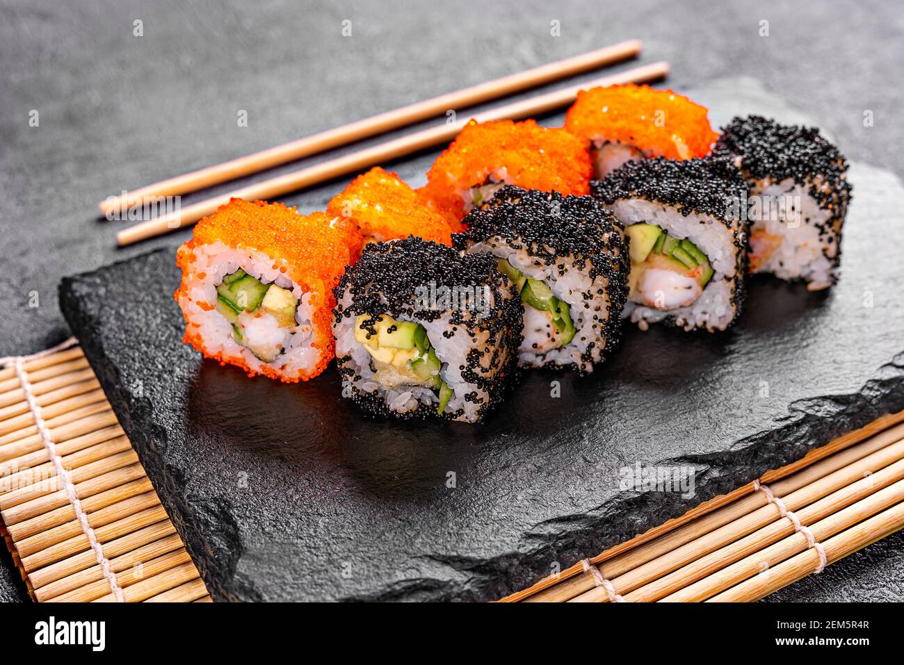 Golden dragon sushi roll with crab, salmon, cucumber, sesame seeds and cream cheese over black backgraund. Top view Stock Photo