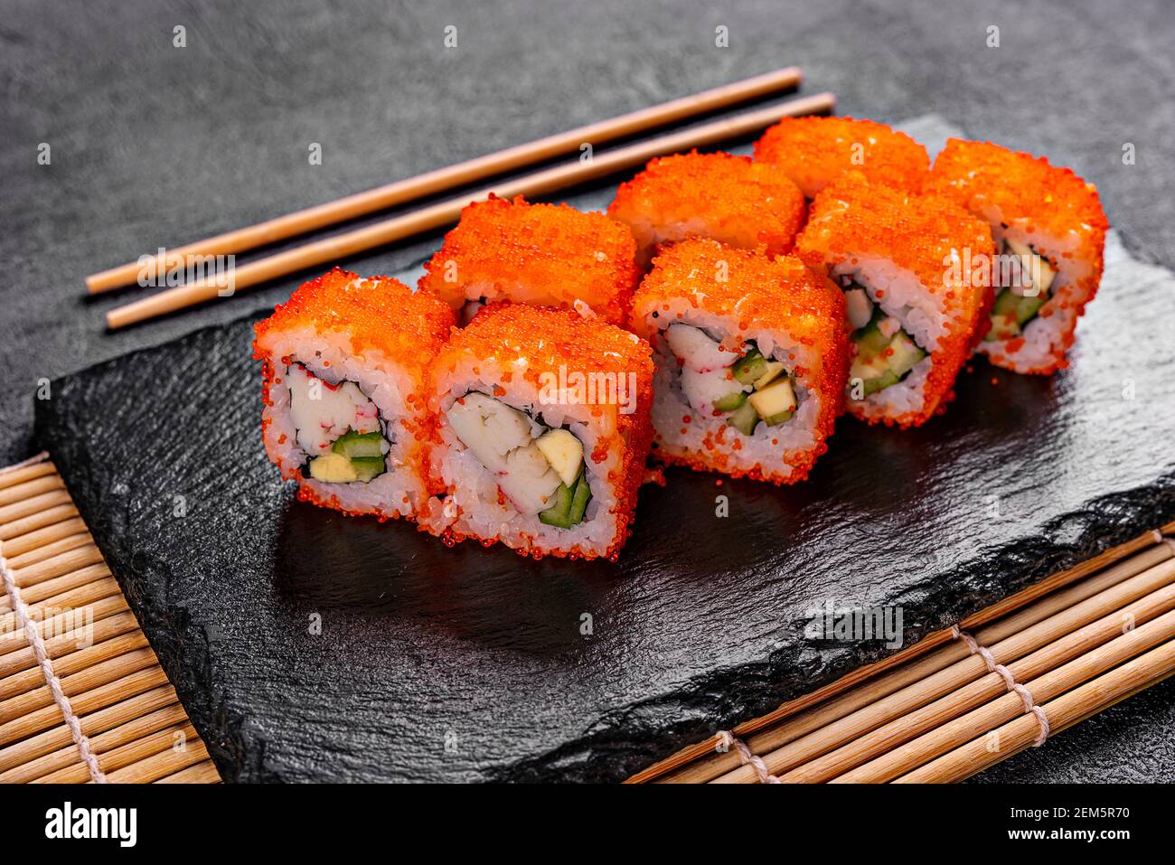 Golden dragon sushi roll with crab, salmon, cucumber, sesame seeds and cream cheese over black backgraund. Top view Stock Photo