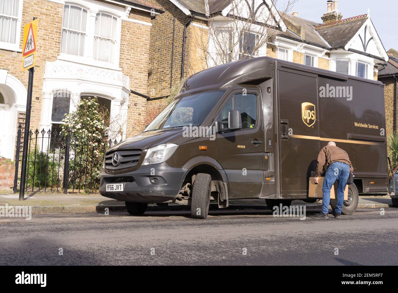 UPS delivery man offloading parcels from van on road side near