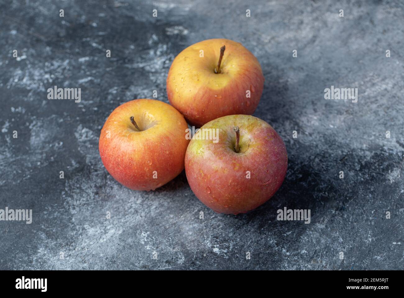 Three fresh red apples on a marble background Stock Photo