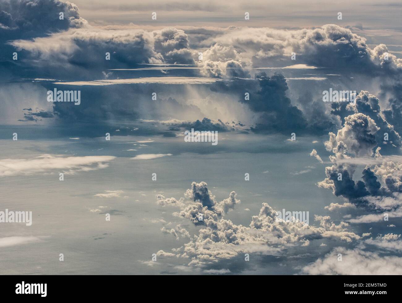 View of the fluffy tropical clouds in the sky above the South China Sea taken from an airplane window with a view of Hong Kong Island below, on a blue sky sunny day on approach to SAR Hong Kong, China, PRC. © Olli Geibel Stock Photo