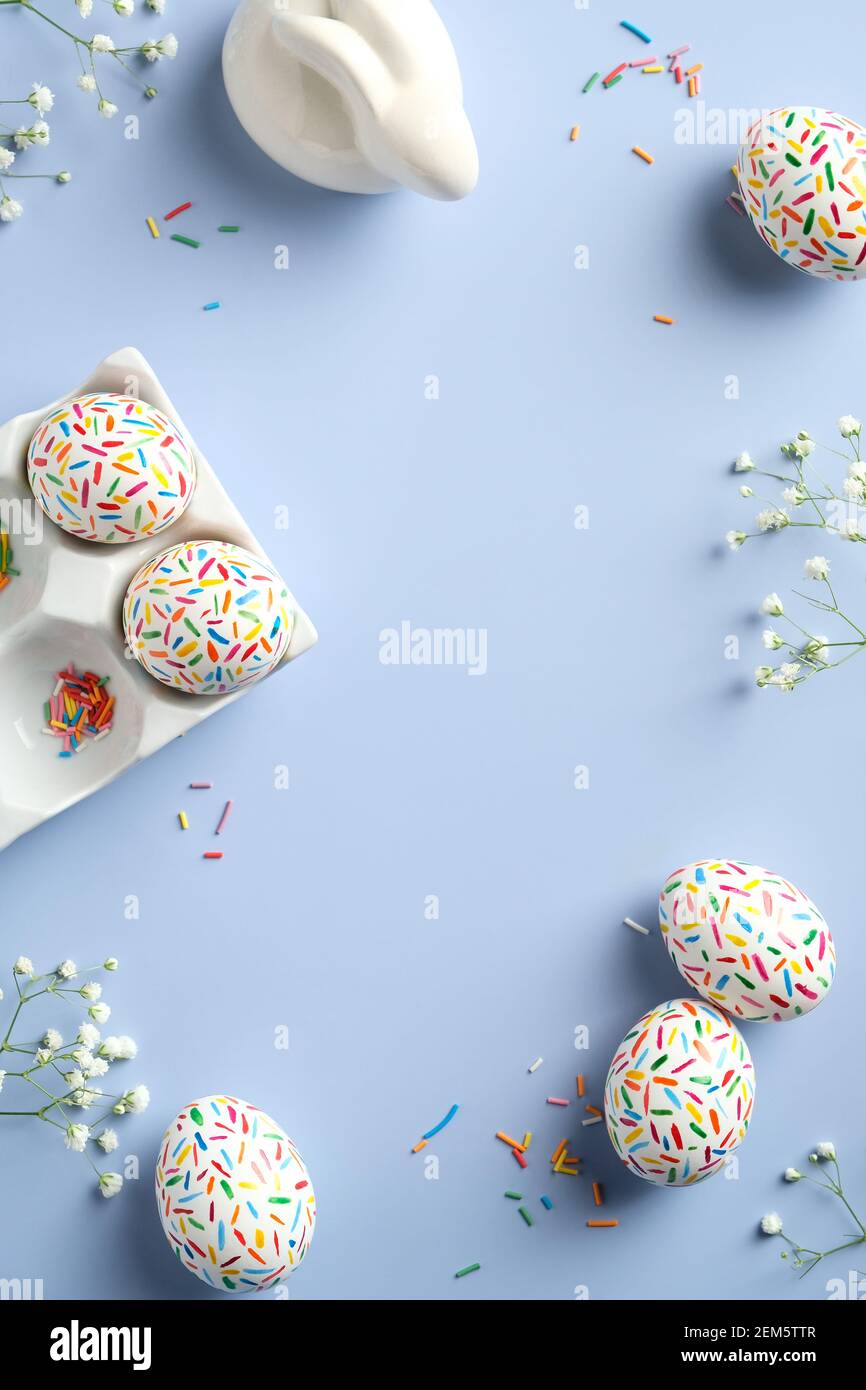 Happy Easter flat lay composition. Colorful Easter eggs, Easter bunny, flowers on blue background. Top view, overhead. Stock Photo