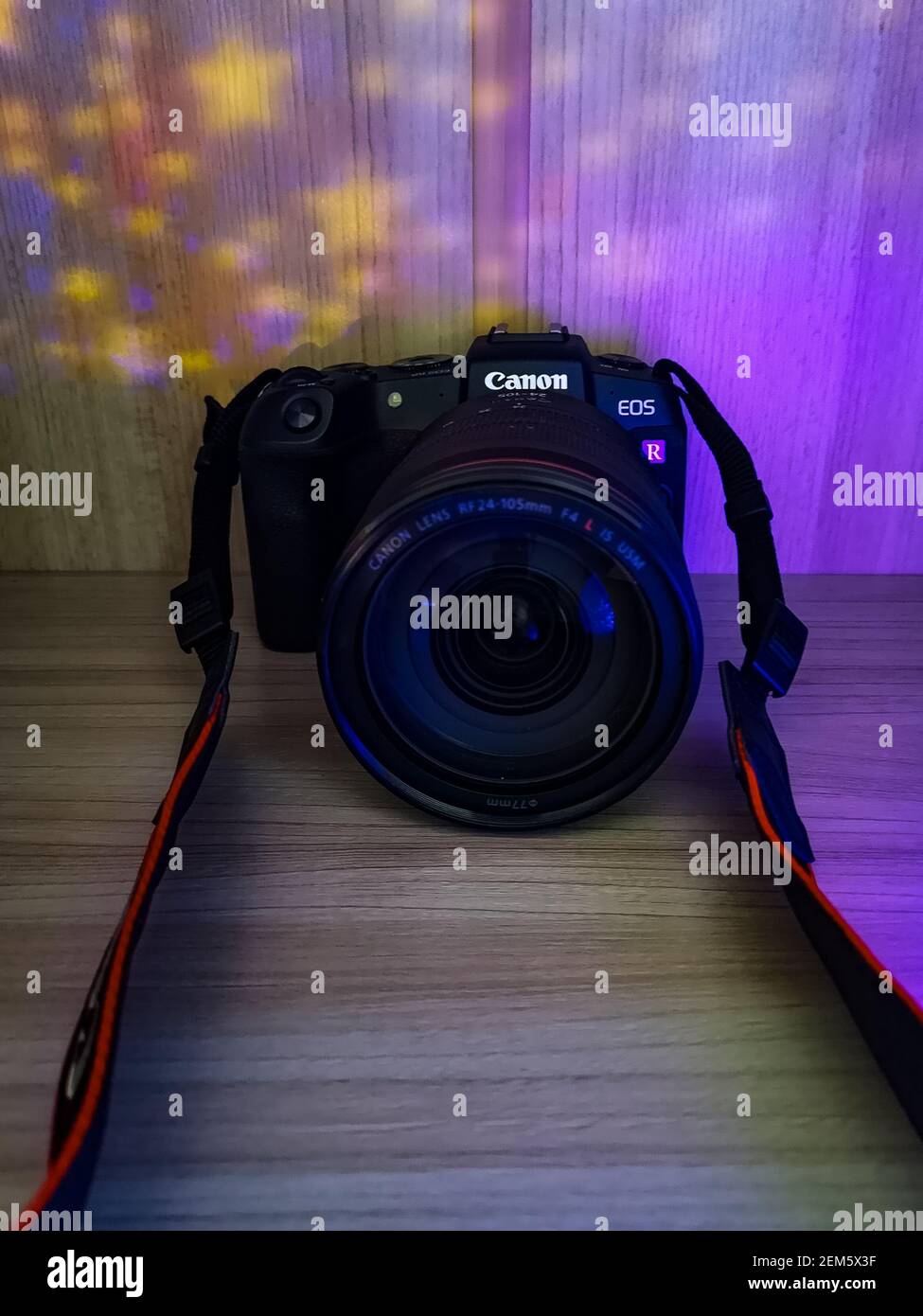 Wroclaw, Poland - April 28 2020: Canon RP camera with lens 24-105 f4 on wooden board highlighted with colorful lights Stock Photo
