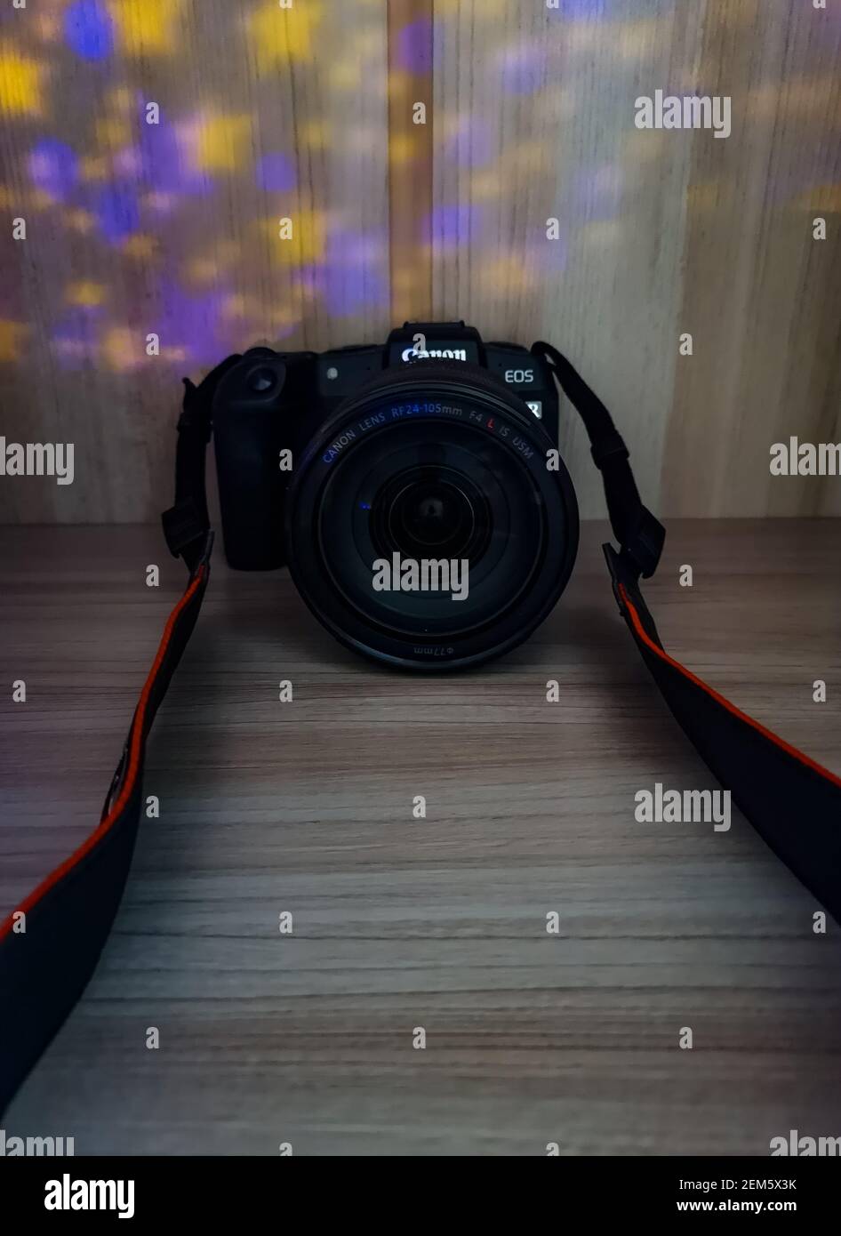 Wroclaw, Poland - April 28 2020: Canon RP camera with lens 24-105 f4 on wooden board highlighted with colorful lights Stock Photo