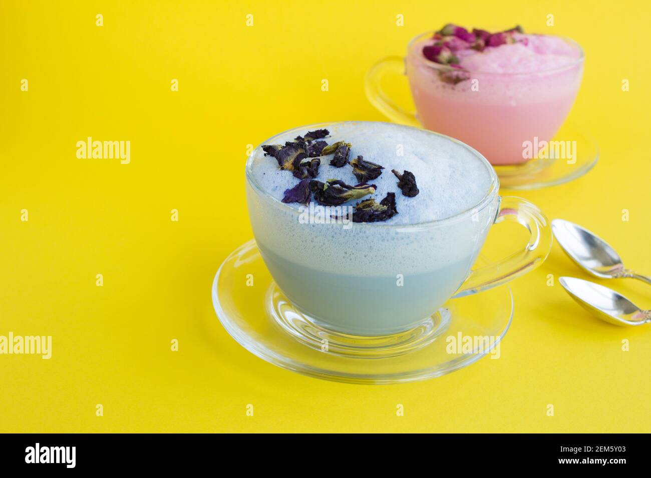 Blue and rose moon milk in glass cups on the yellow surface. Copy space. Stock Photo
