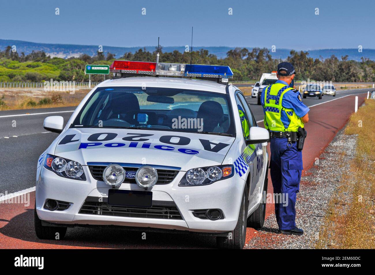 A Australian traffic policeman at work aiming his speed camera at traffic on a highway Stock Photo