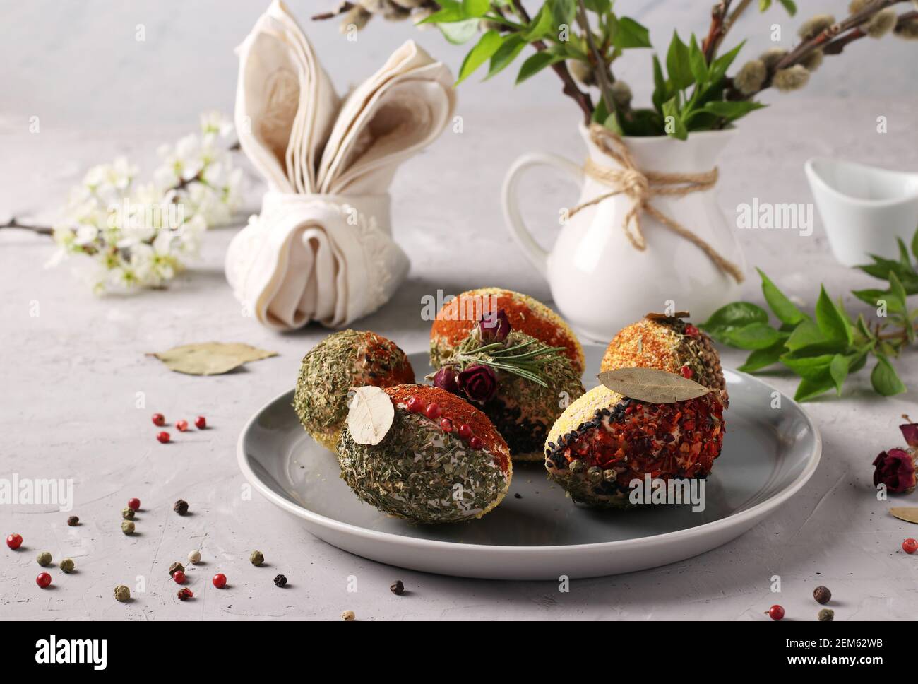 Easter eggs decorated with different spices and cereals without dyes and preservatives on a plate on a gray concrete background. Stock Photo