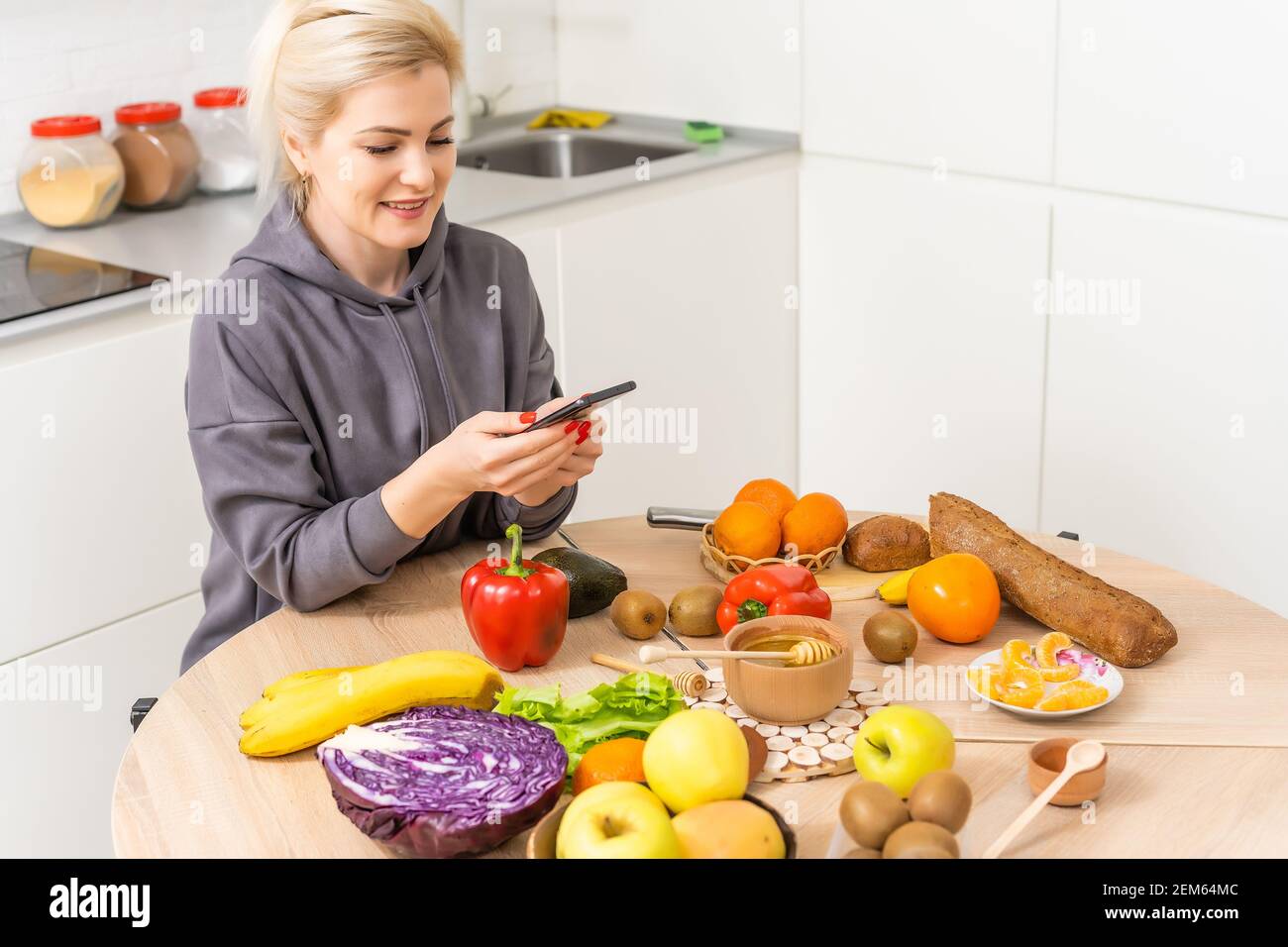 Food delivery service woman holding smartphone in front of vegetables