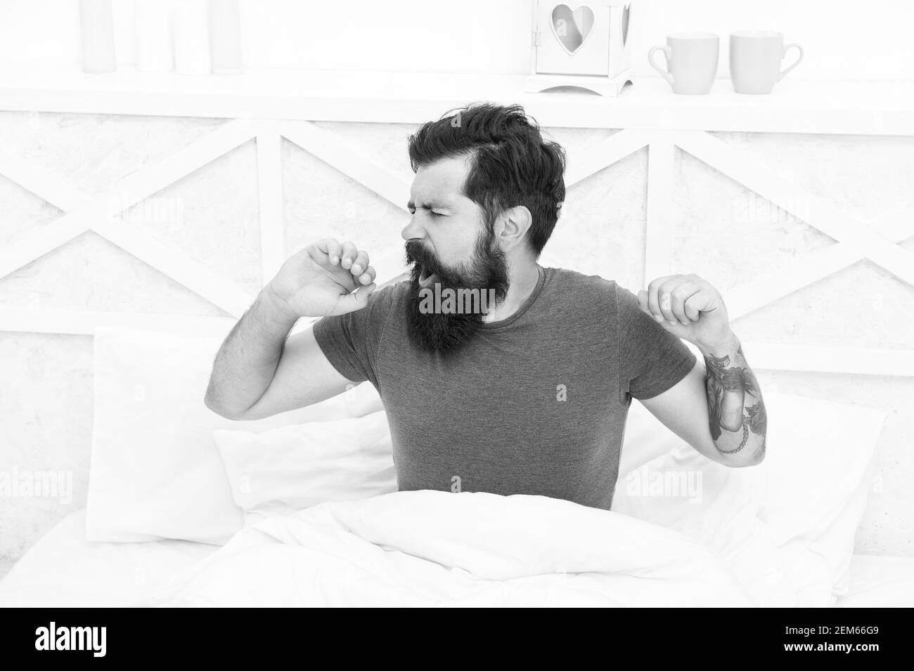 relaxed yawning man waking up in the morning in bed at home, lazy sunday. Stock Photo